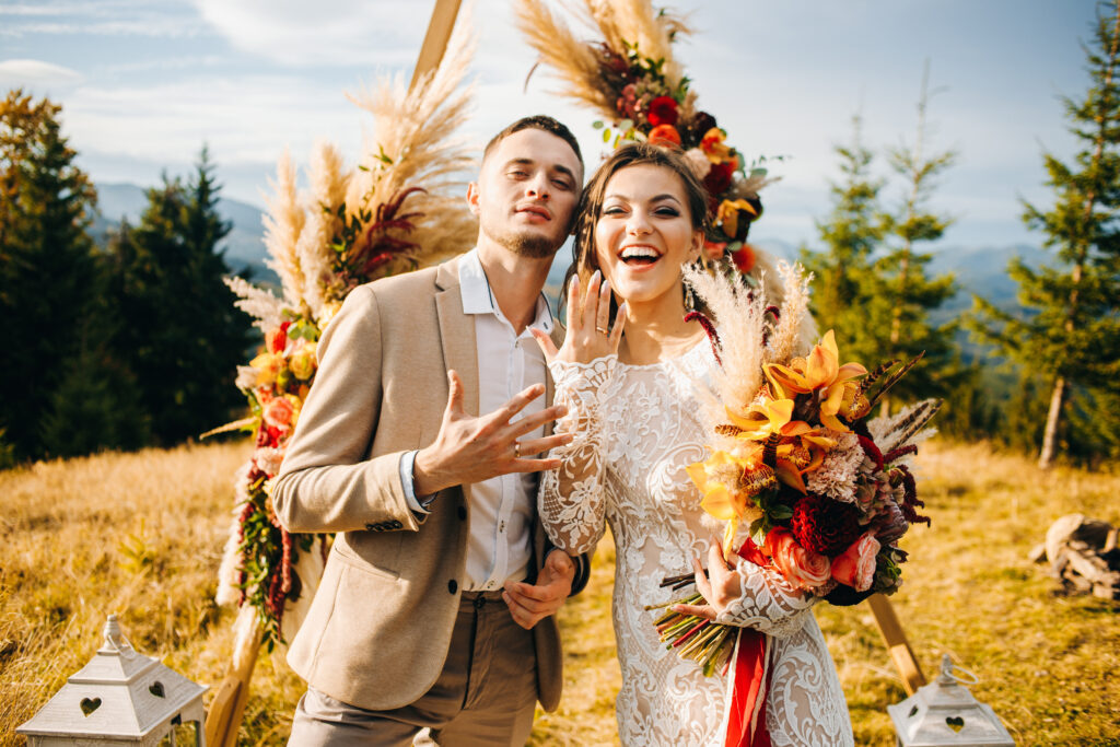 Wedding ceremony under the arch decorated with flowers. Charming couple showing off their wedding rings